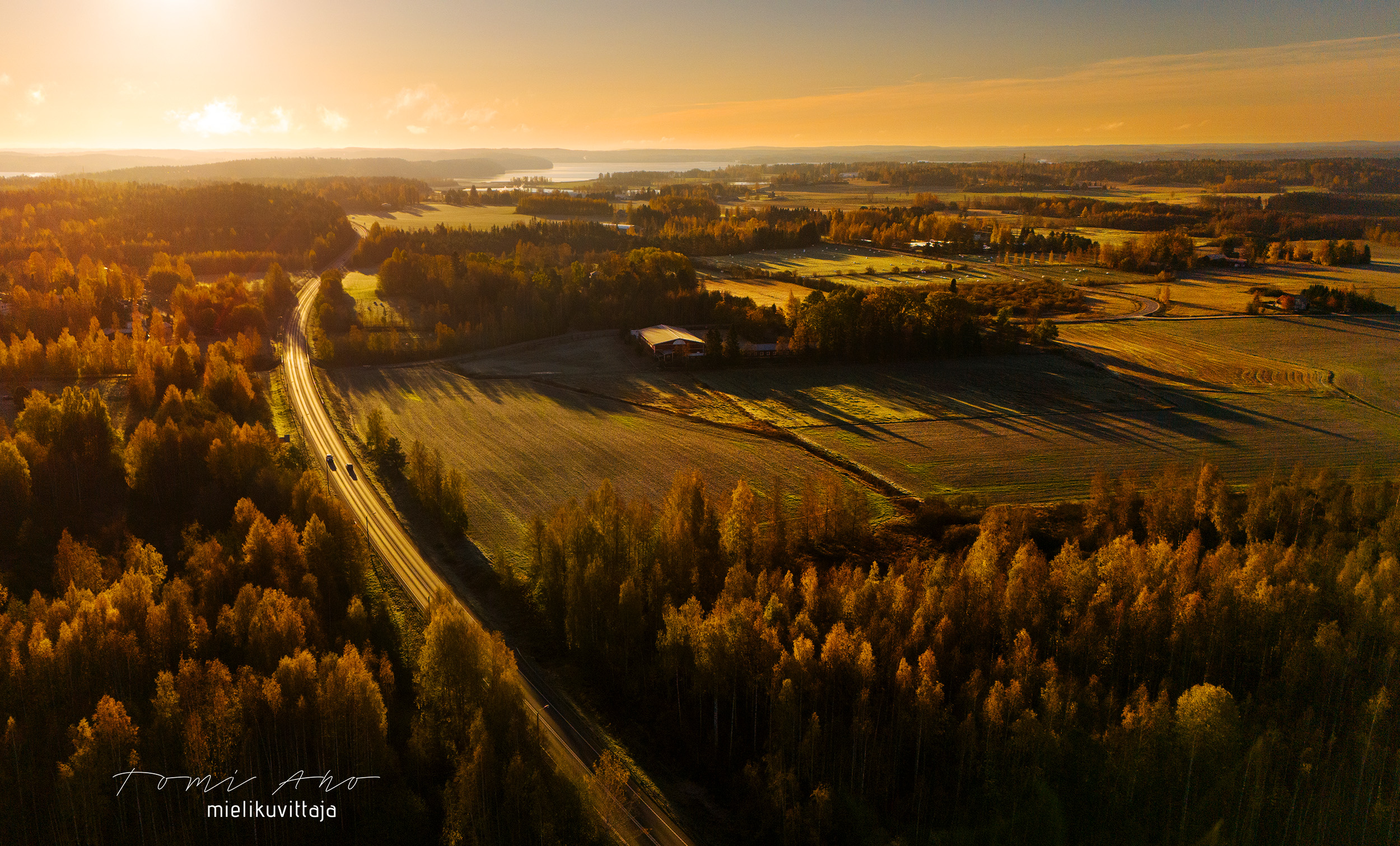 Mielikuvittaja dronekuva maisemasta, jonka tie halkaisee auringon laskiessa. 